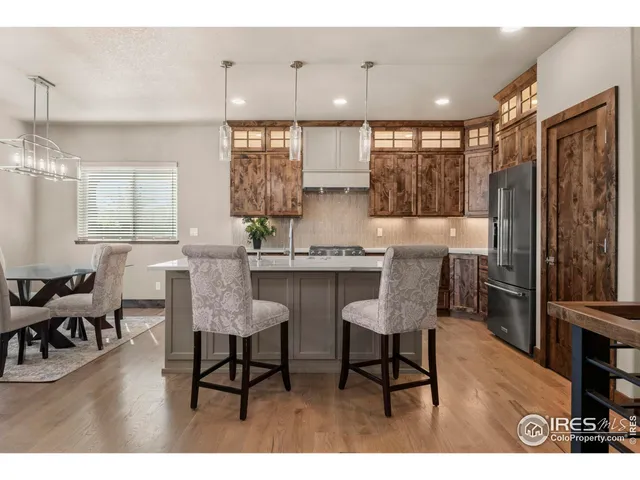 a kitchen with kitchen island granite countertop a stove a sink a oven and a dining table with wooden floor