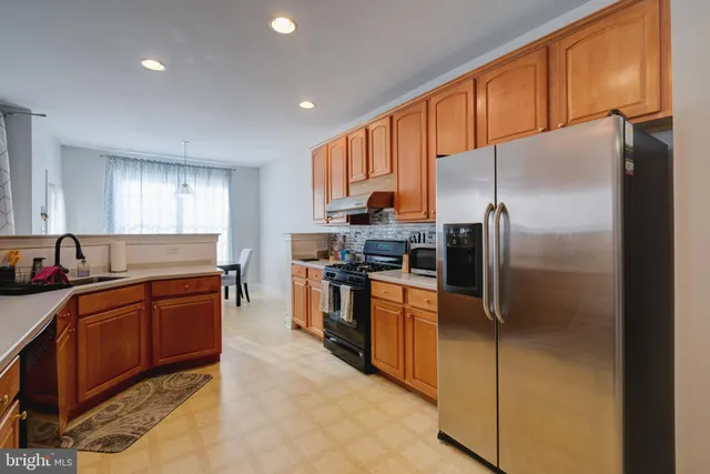 a kitchen with stainless steel appliances granite countertop a refrigerator a stove and a sink
