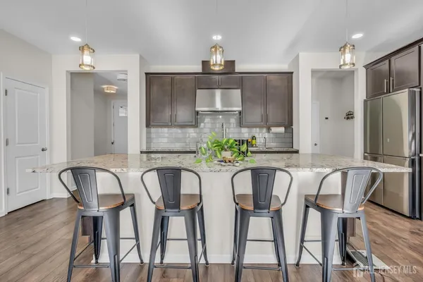 a kitchen with stainless steel appliances a dining table chairs and wooden floor