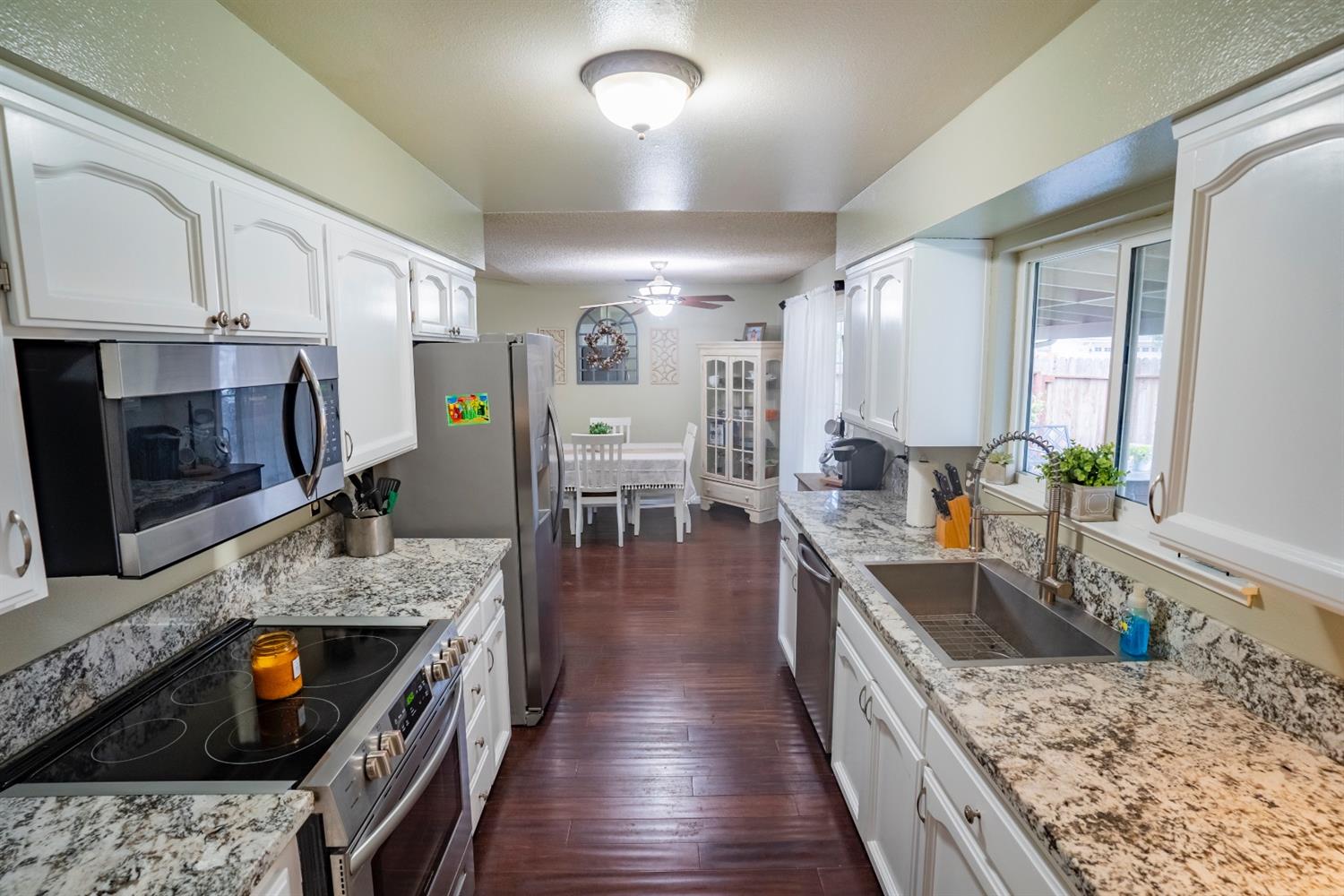 1607 Ashlan Avenue Clovis, CA 93611 - Photo 3 of 17 a kitchen with stainless steel appliances granite countertop a stove top oven a sink dishwasher a dining table and chairs with wooden floor