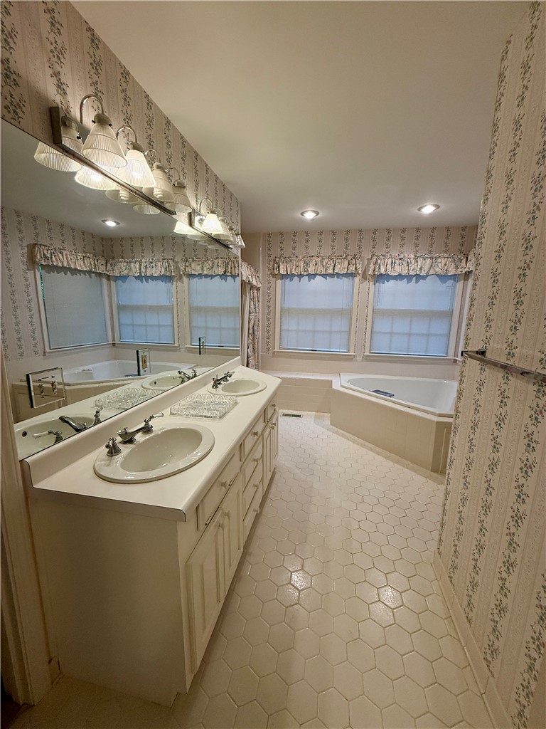 235 Stonehaven Way Seneca, SC 29672 - Photo 28 of 35 An inviting primary bathroom features a double vanity and a corner soaking tub set against hexagon tiled flooring.