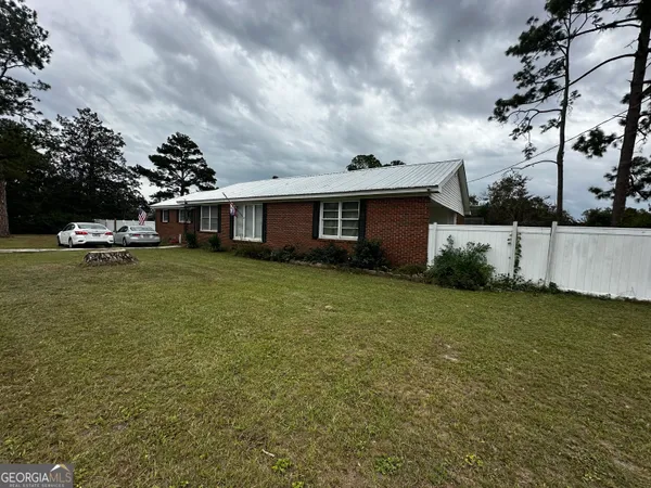 a view of a house with a big yard and large trees
