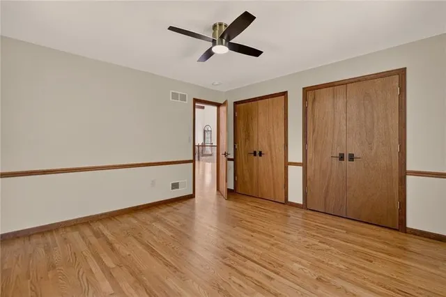 an empty room with wooden floor and a ceiling fan