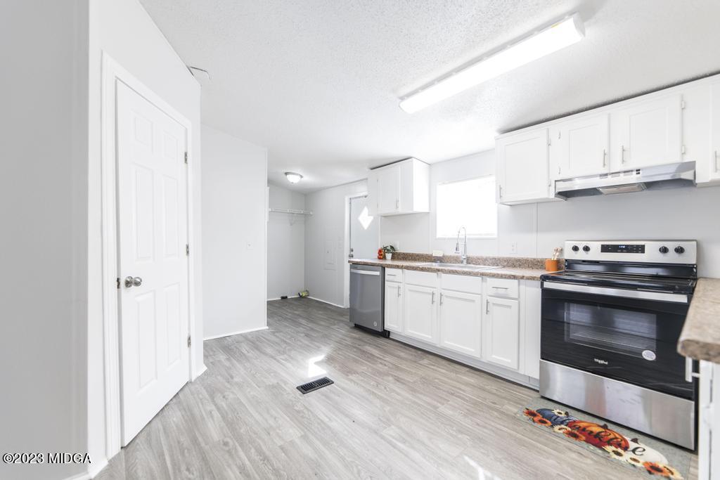 208 Colonial Drive Byron, GA 31008 - Photo 13 of 38 a kitchen with granite countertop a stove top oven a sink dishwasher and a refrigerator with wooden floor