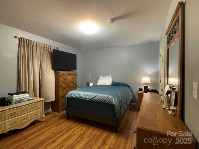 a bedroom with a bed and a flat tv screen on dresser