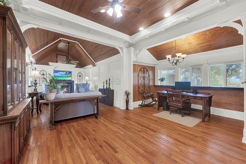 1425 Lone Star Road Celina, TX 75009 - Photo 9 of 40 This expansive family room blends warmth and functionality with rich wood ceilings, original hardwood floors, elegant millwork, and a cozy fireplace. A dedicated office nook with built-in workspace overlooks the grounds, while abundant natural light and an open layout create an inviting space for everyday living, working from home, or entertaining.