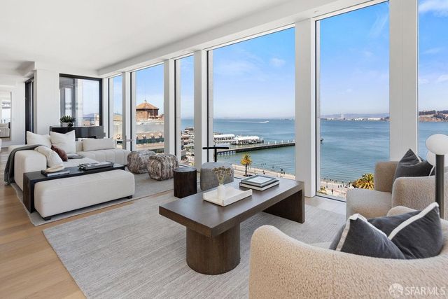 a large white kitchen with kitchen island a large counter top space a sink a window and stainless steel appliances