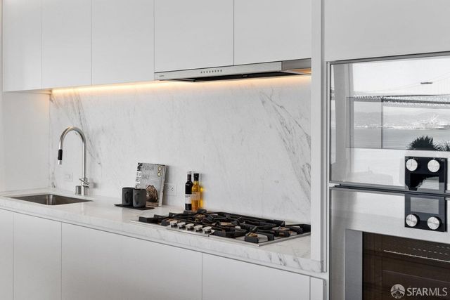 a view of a hallway with wooden floor a glass door and a bathroom