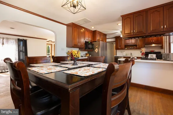 a kitchen with stainless steel appliances kitchen island granite countertop a stove a sink dishwasher and white cabinets with wooden floor