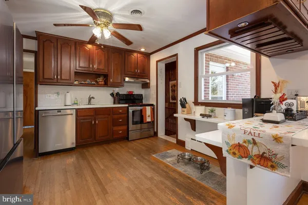 a kitchen with stainless steel appliances granite countertop a refrigerator a sink dishwasher a dining table and chairs with wooden floor
