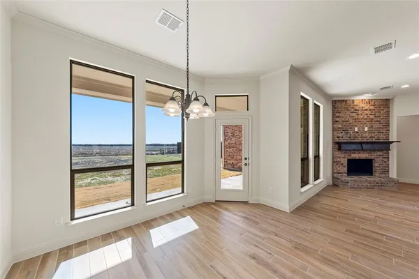 a view of an empty room with wooden floor fireplace and a window