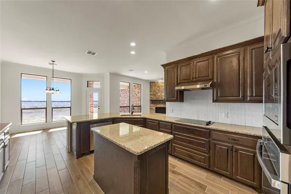 a kitchen with stainless steel appliances granite countertop a sink dishwasher stove and wooden cabinets with wooden floor