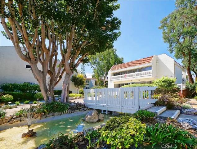 a view of a back yard with plants and large trees