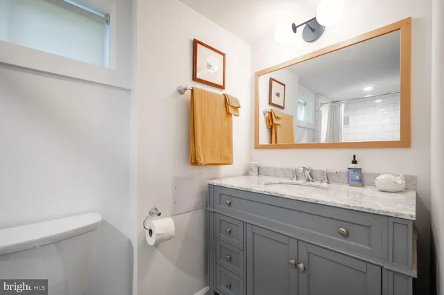 a bathroom with a granite countertop sink mirror and a toilet