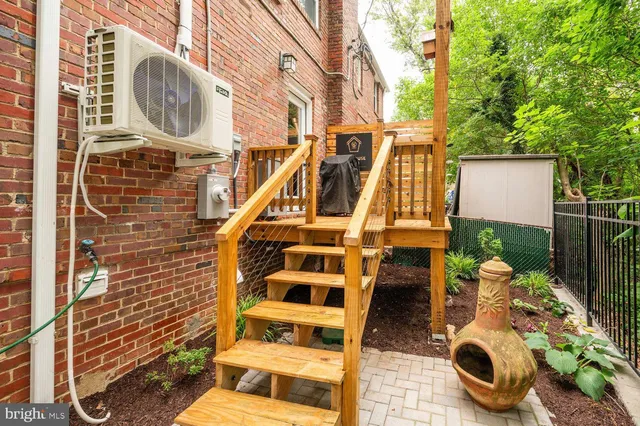 a brick house with a yard plants and large tree