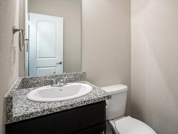 a bathroom with a granite countertop sink a toilet and mirror