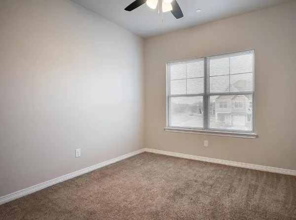 an empty room with a window and a ceiling fan