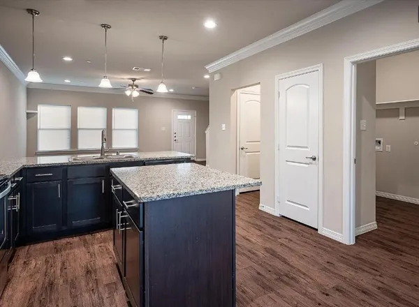 an open kitchen with a refrigerator and wooden floor