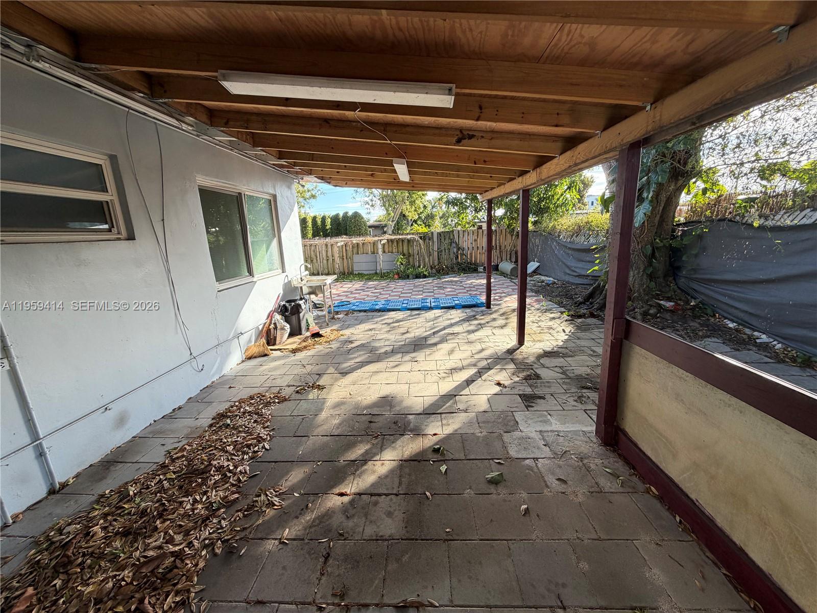 4210 Southwest 10th Street Plantation, FL 33317 - Photo 18 of 19 a view of a patio with table and chairs under an umbrella with a view of the back yard