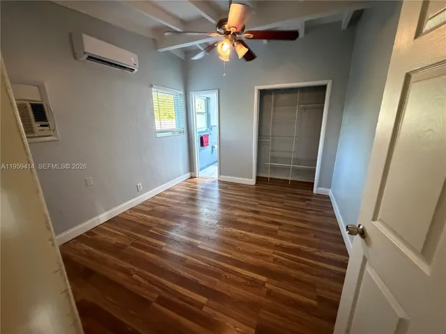 a view of an empty room with wooden floor and a ceiling fan