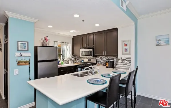 a kitchen with stainless steel appliances granite countertop a refrigerator a stove a sink a dining table and chairs