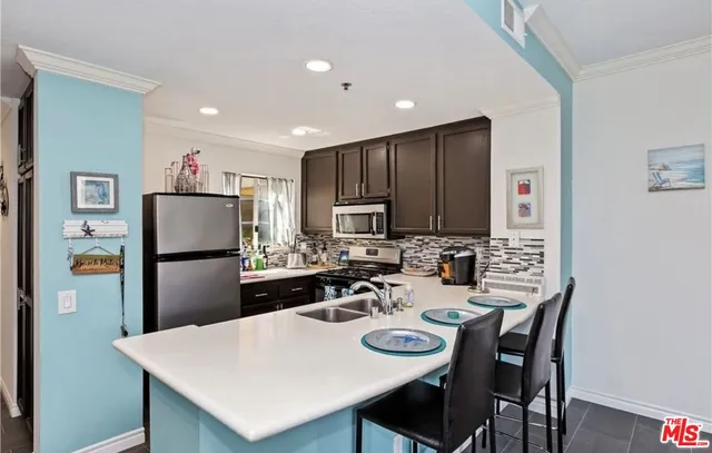 a kitchen with stainless steel appliances granite countertop a refrigerator a stove a sink a dining table and chairs