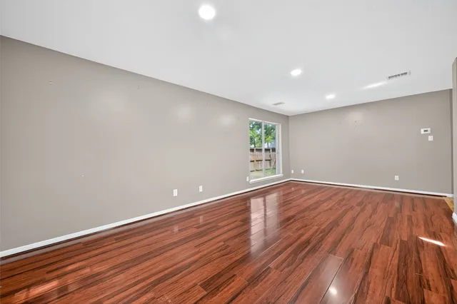a view of an empty room with wooden floor and window