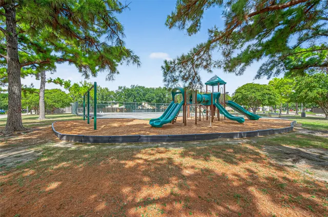 a view of a park with swings and a large tree