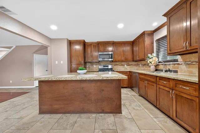 a kitchen with stainless steel appliances granite countertop a sink counter space cabinets and a large window