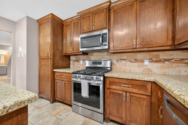 a kitchen with stainless steel appliances granite countertop a stove microwave and refrigerator