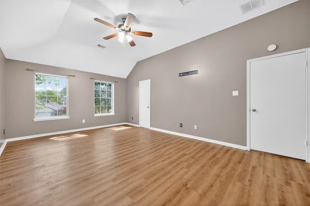 a view of an empty room with window and wooden floor