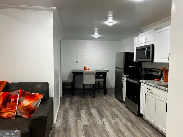 a kitchen with stainless steel appliances granite countertop a stove top oven a sink dishwasher and a refrigerator with wooden floor