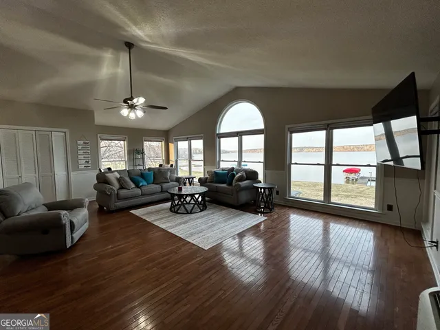 a living room with furniture floor to ceiling window and wooden floor