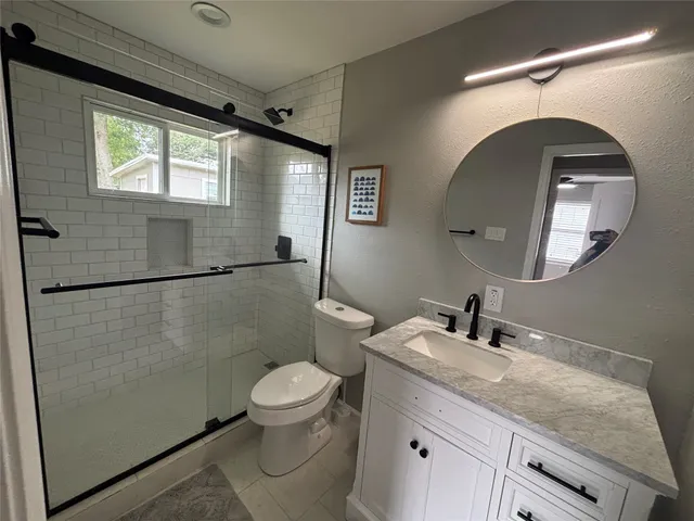 a bathroom with a granite countertop sink mirror vanity and toilet