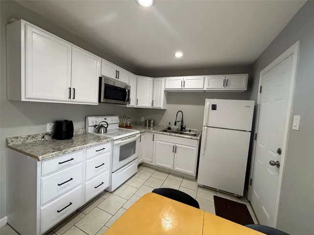 a kitchen with white cabinets sink and white appliances