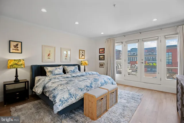 a spacious bedroom with a bed a dresser and a large window