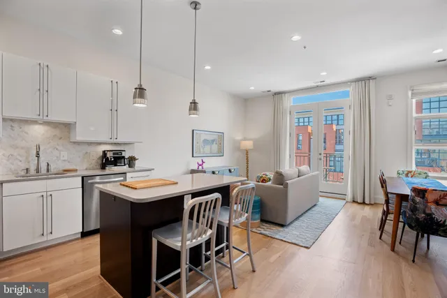 a kitchen with stainless steel appliances granite countertop a sink a stove a dining table and chairs with wooden floor