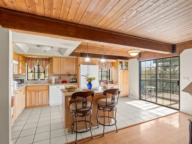 a kitchen with stainless steel appliances kitchen island granite countertop a table chairs and a refrigerator