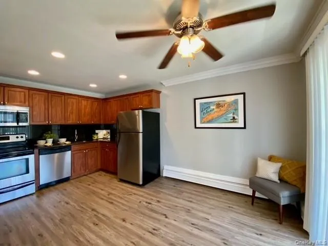 a kitchen with stainless steel appliances kitchen island granite countertop a refrigerator a sink a stove and a wooden floors