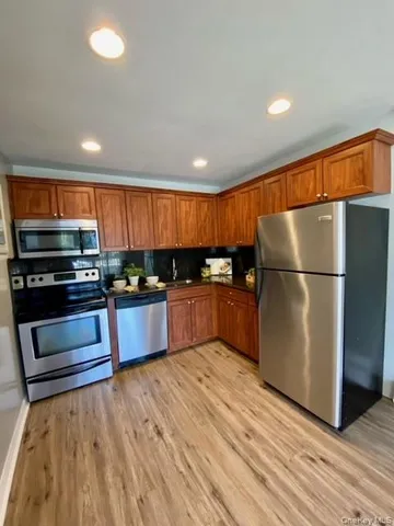 a kitchen with stainless steel appliances kitchen island granite countertop a refrigerator and a stove top oven