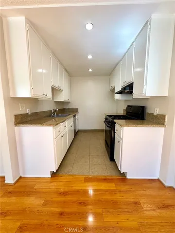 a kitchen with granite countertop a stove top oven sink and cabinets