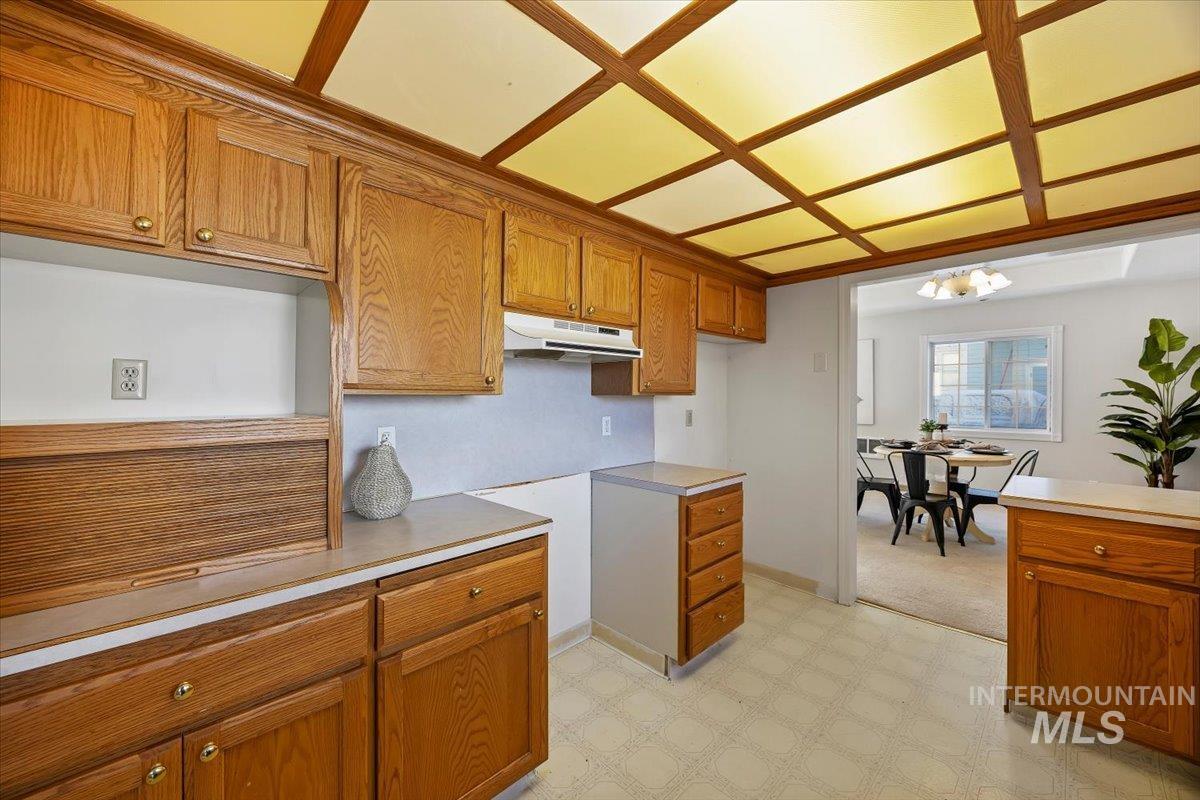 717 E Street Rupert, ID 83350 - Photo 14 of 24 Kitchen featuring light floors, brown cabinetry, light countertops, under cabinet range hood, and a chandelier