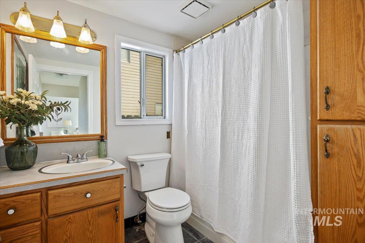 717 E Street Rupert, ID 83350 - Photo 18 of 24 Full bathroom featuring a shower with shower curtain, vanity, and dark tile patterned flooring