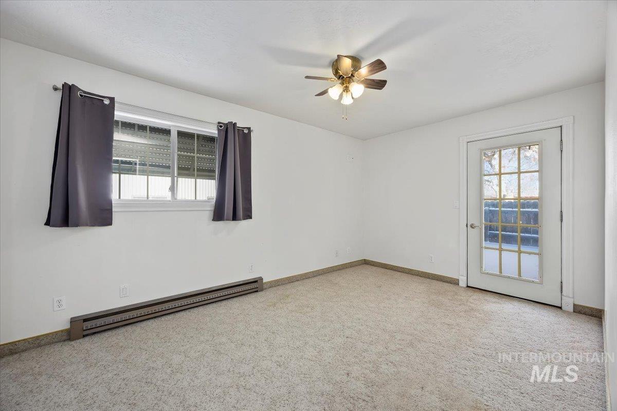 717 E Street Rupert, ID 83350 - Photo 19 of 24 Spare room featuring a baseboard radiator, light carpet, plenty of natural light, and ceiling fan