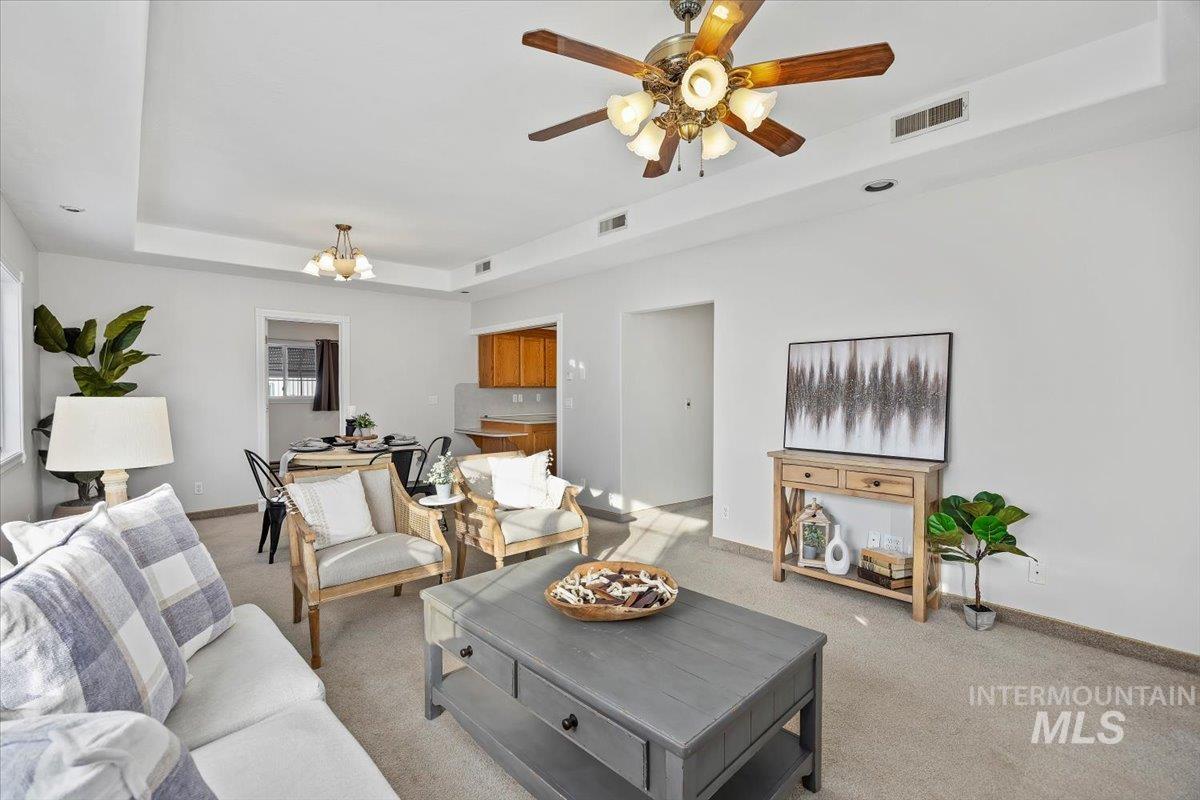 717 E Street Rupert, ID 83350 - Photo 4 of 24 Carpeted living room with a raised ceiling, a chandelier, and a ceiling fan