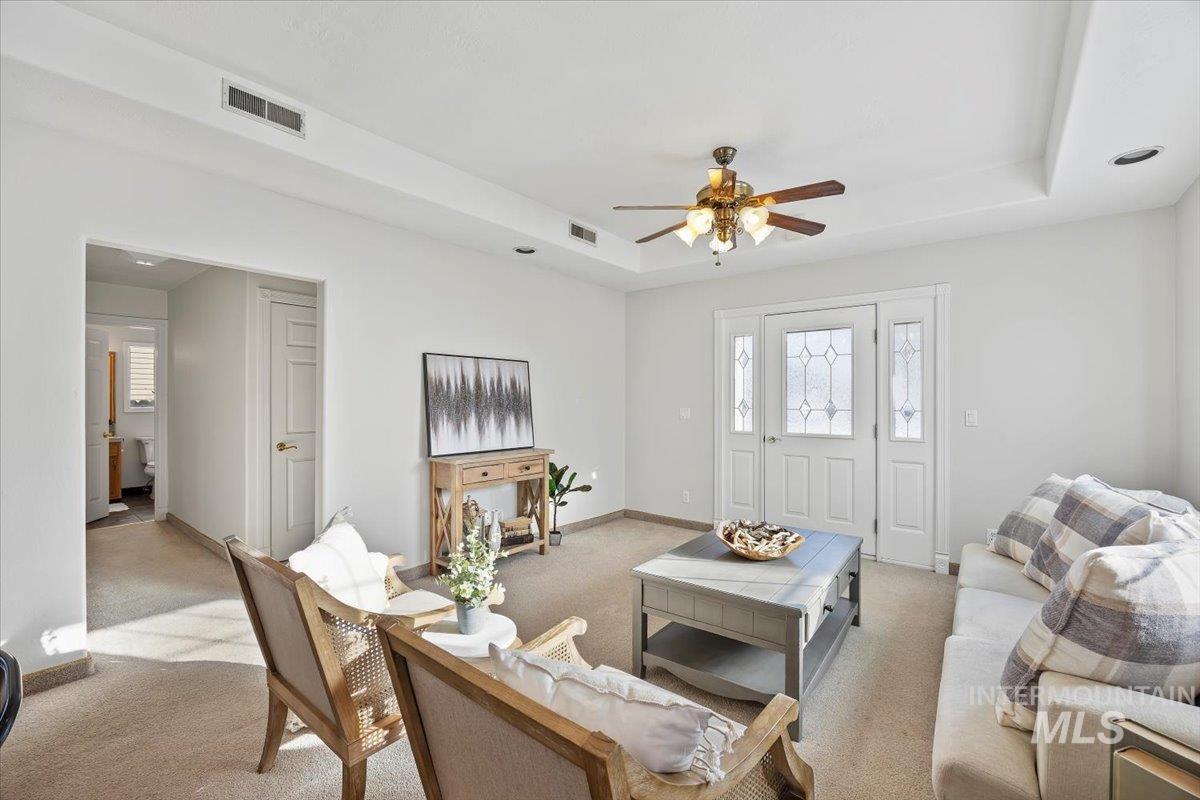 717 E Street Rupert, ID 83350 - Photo 6 of 24 Carpeted living area with a raised ceiling and ceiling fan