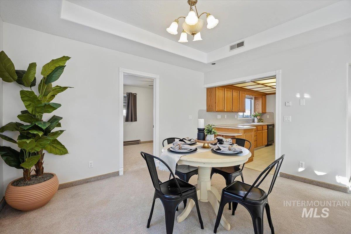 717 E Street Rupert, ID 83350 - Photo 7 of 24 Dining area with a chandelier, a raised ceiling, and light colored carpet