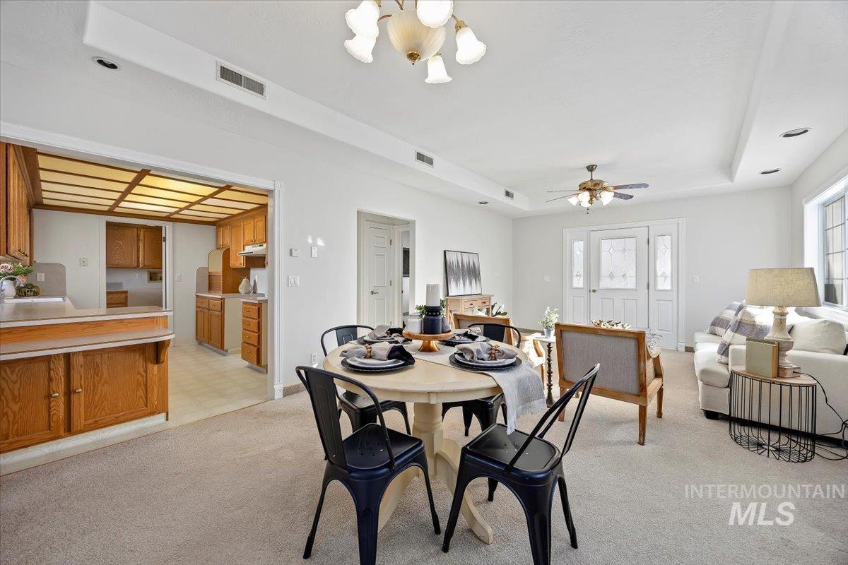 717 E Street Rupert, ID 83350 - Photo 8 of 24 Dining area with a raised ceiling, light colored carpet, a chandelier, ceiling fan, and light flooring