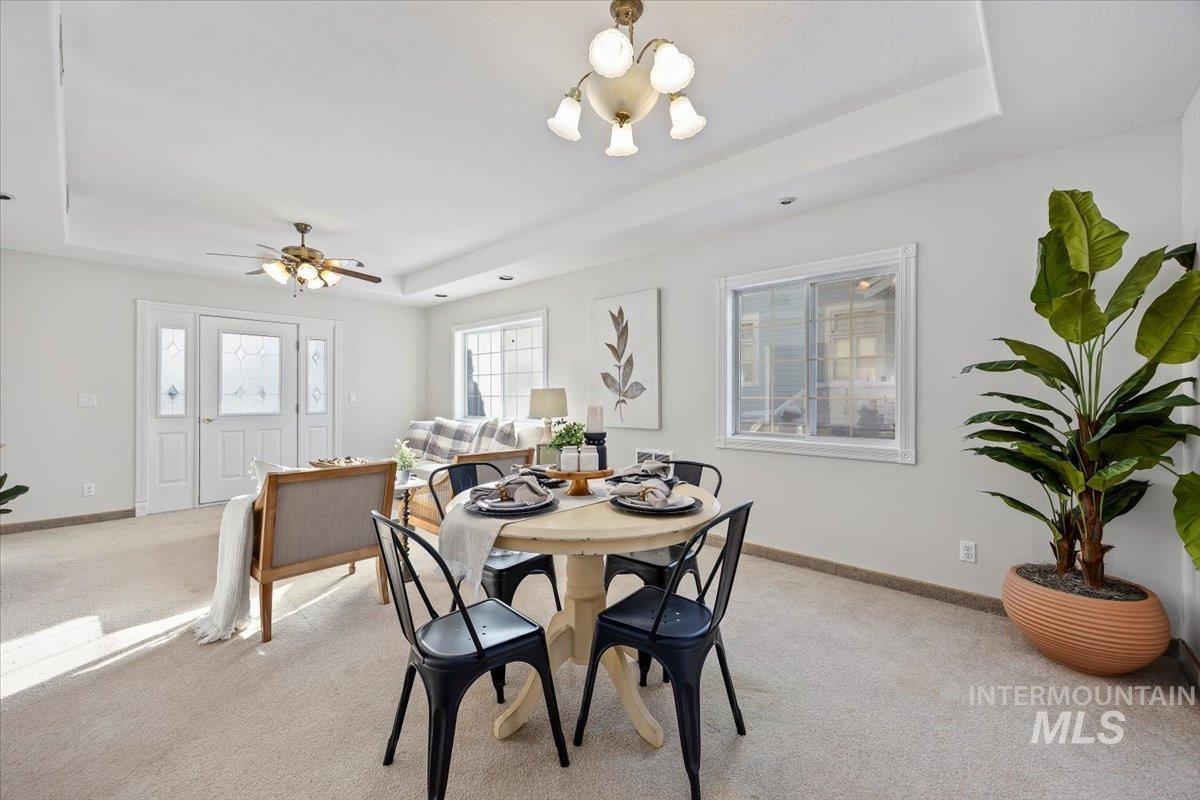 717 E Street Rupert, ID 83350 - Photo 9 of 24 Carpeted dining room with a tray ceiling, a chandelier, and a ceiling fan