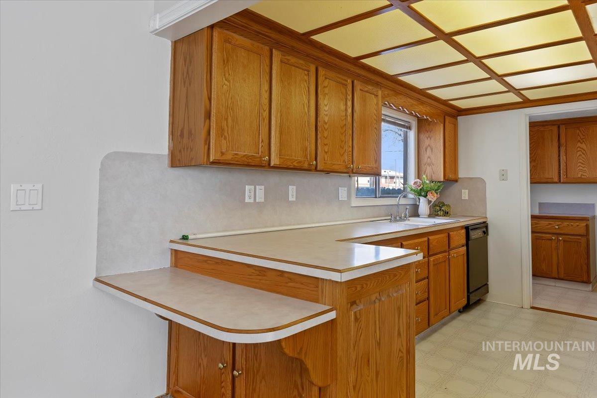 717 E Street Rupert, ID 83350 - Photo 10 of 24 Kitchen with light flooring, brown cabinetry, light countertops, a peninsula, and a breakfast bar